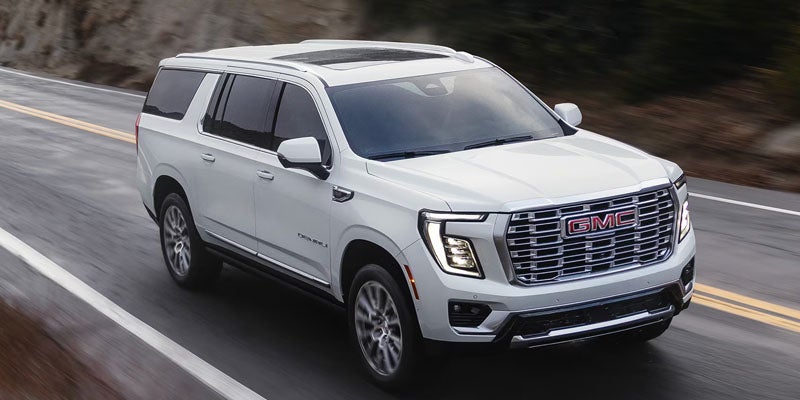 A white GMC SUV is being driven on a country highway.